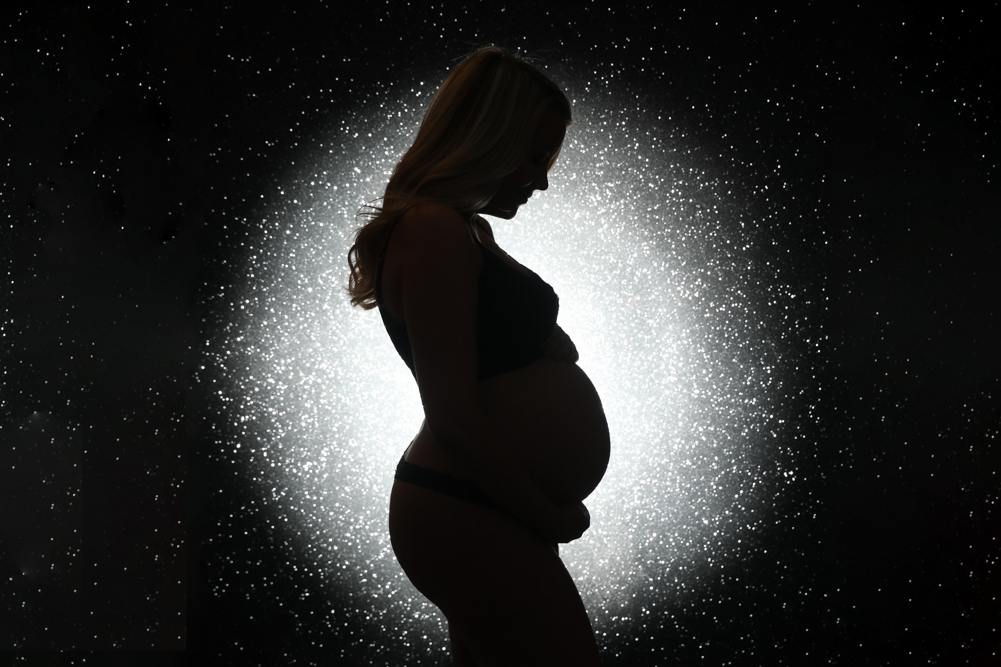 bump to baby photoshoot Liverpool silhouette of a pregnant lady in a spotlight on a sparkly backdrop
