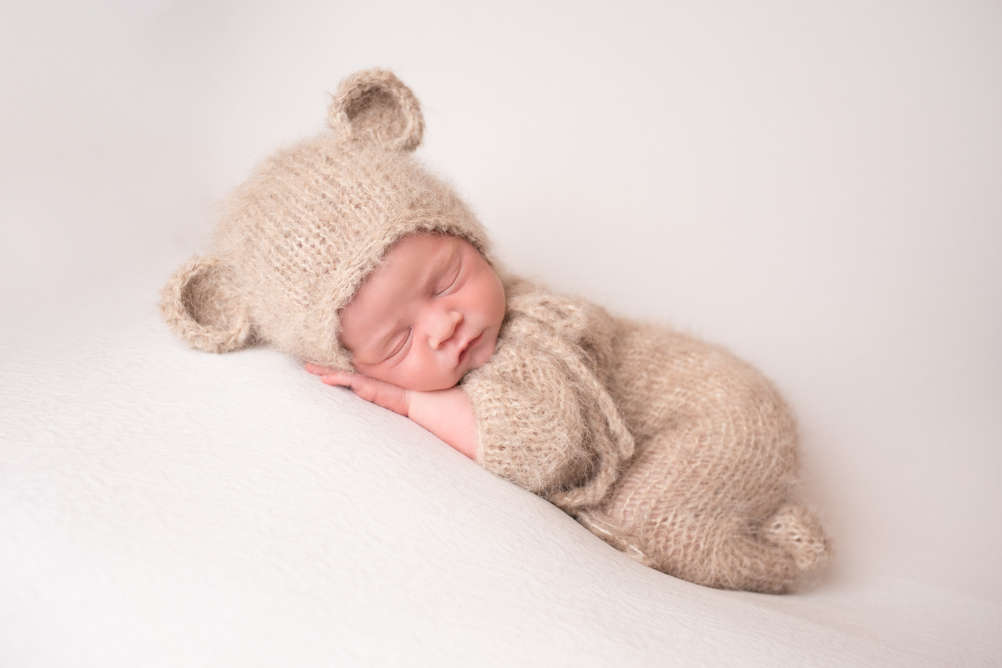 newborn photoshoot baby asleep dressed as teddy bear