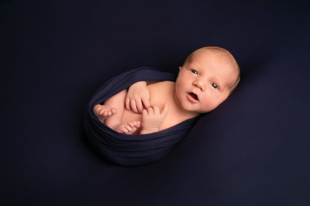 baby boy photoshoot awake on navy blue backdrop