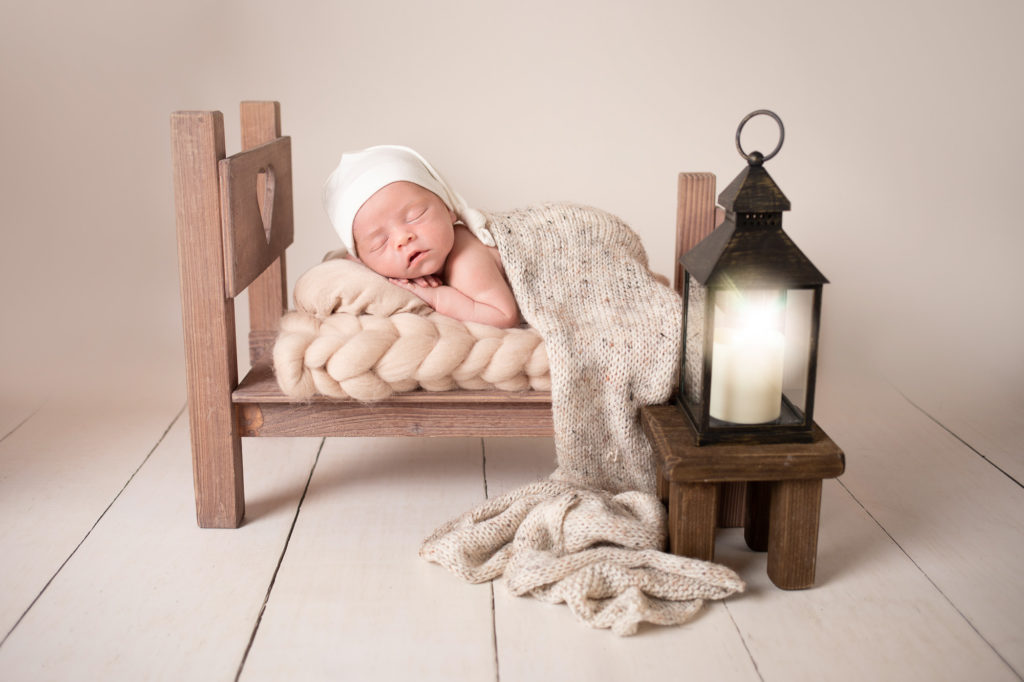 newborn baby portrait in tiny brown bed sleeping