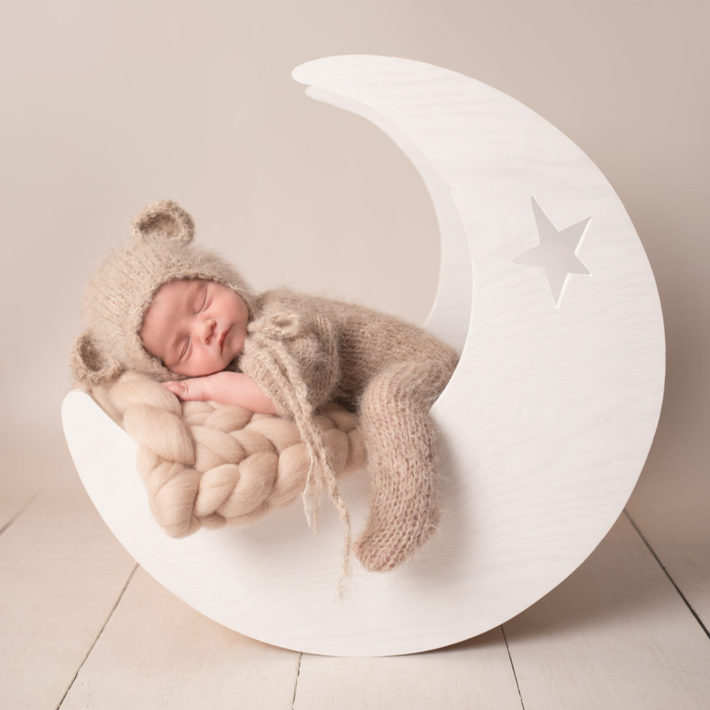 newborn photoshoot baby dressed as teddy bear sleeping in moon prop