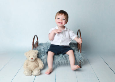 Little sitters baby toddler Photoshoot Peekaboo Liverpool little boy sitting on miniature bed prop with teddy