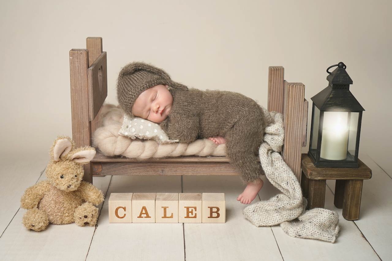 Newborn photoshoot Peekaboo Liverpool sleeping baby in knit outfit on baby bed prop with personalised details