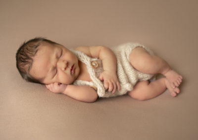 Newborn photoshoot Peekaboo Liverpool baby in cream knit romper on neutral backdrop