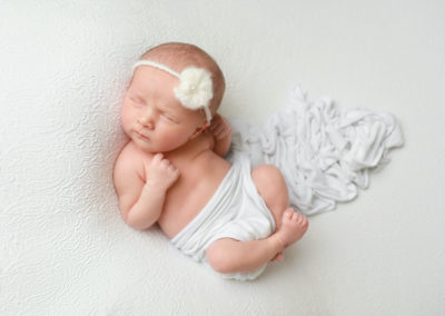 Newborn photoshoot Peekaboo Liverpool baby girl posed on white background flower headband