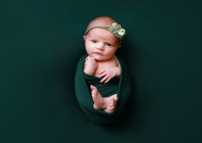 Newborn photoshoot Peekaboo Liverpool baby girl eyes open in deep green wrap