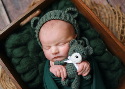 Newborn photoshoot Peekaboo Liverpool deep green holding tiny teddy
