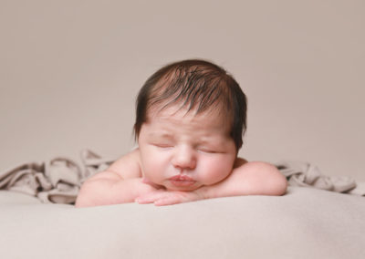 Newborn photoshoot Peekaboo Liverpool sleeping baby with dark hair on neutral backdrop