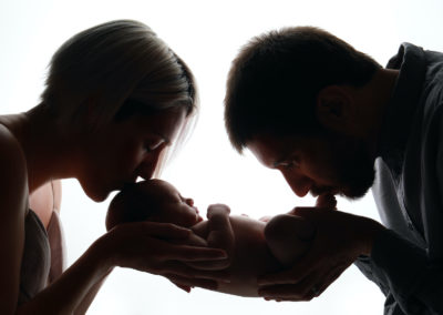 Newborn photoshoot Peekaboo Liverpool mum and dad cradling baby kissing toes